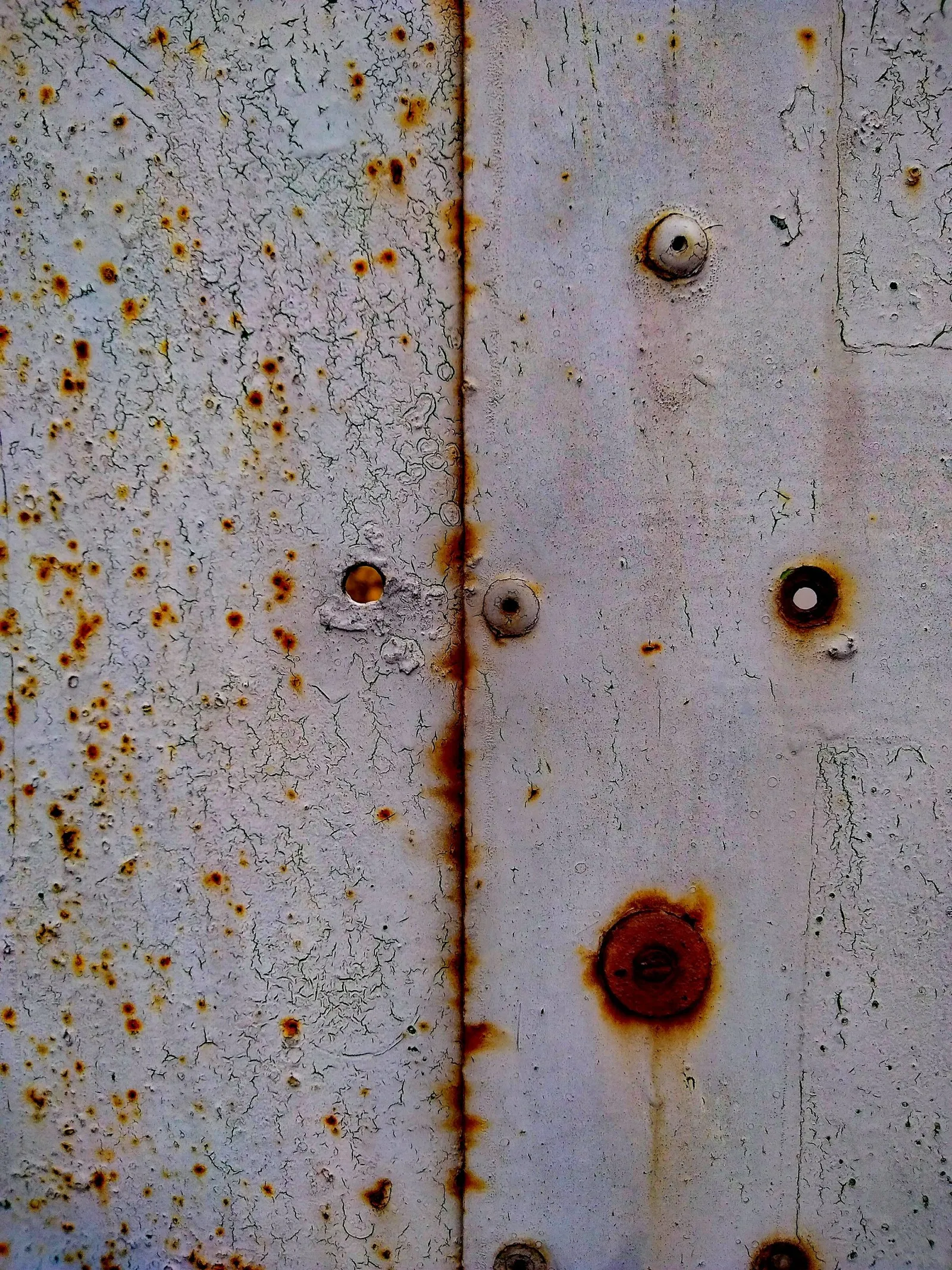 Riveted metal plate marked by rust
